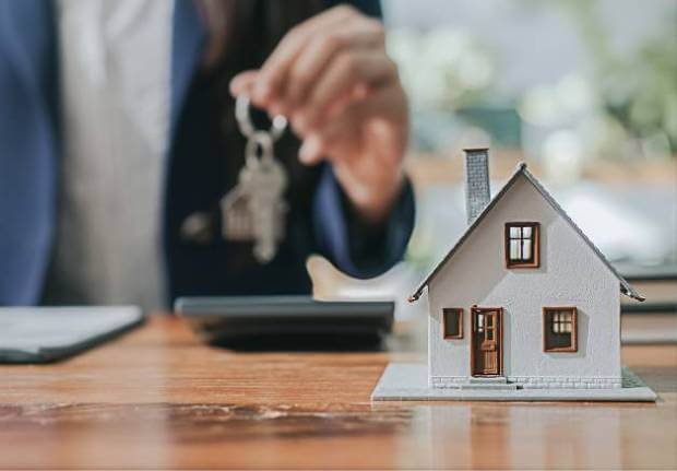 Mini Model house and a man holding a key in the background